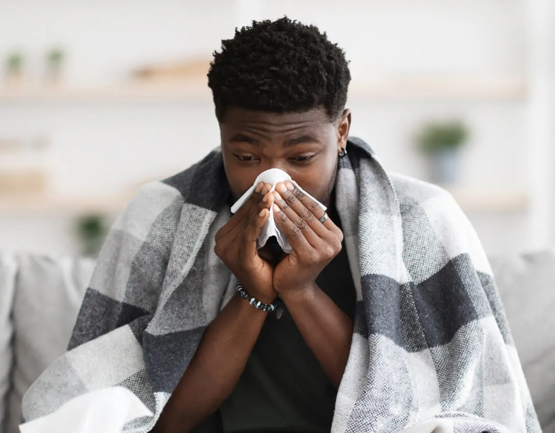 Man blowing nose into tissue suffering from flu