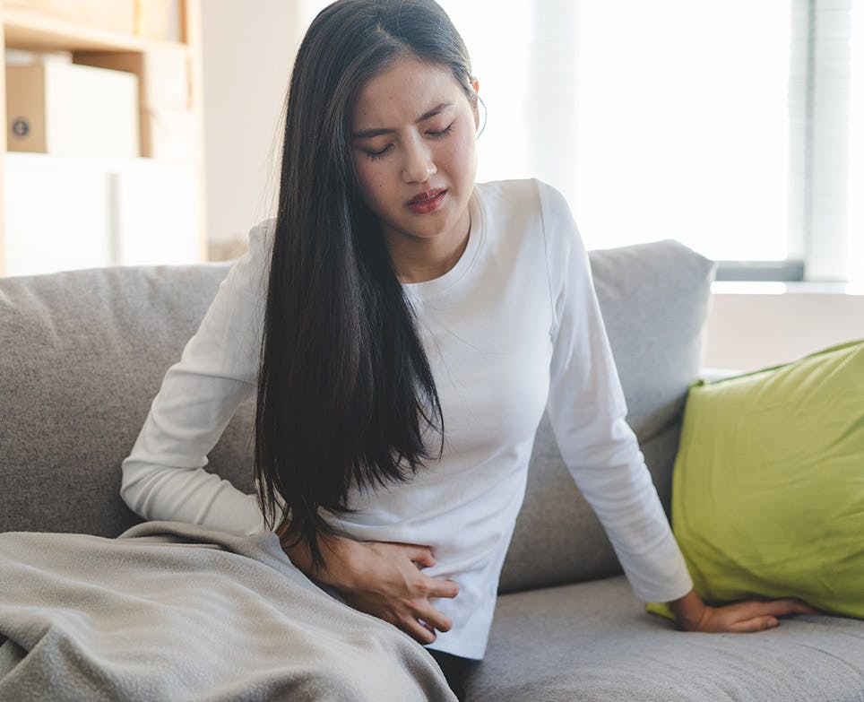 Mujer joven tocando su abdomen en señal de dolor menstrual.