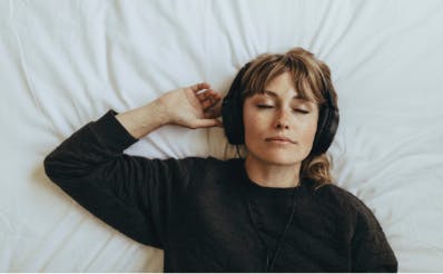 Girl lying on bed with headphones on