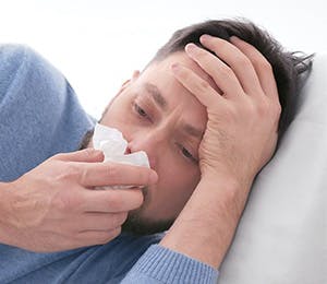 Hombre con síntomas gripales limpiando su nariz. 