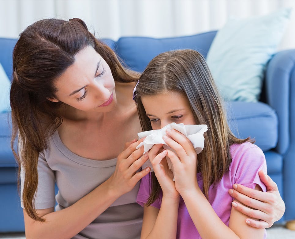 Madre cuidando a su hija, que tiene síntomas gripales. 