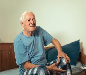 Adulto mayor sujetando su rodilla en señal de dolor. 
