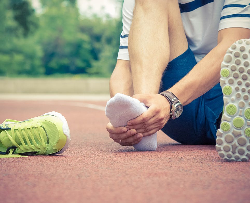 Deportista sujetando su pie en señal de dolor. 