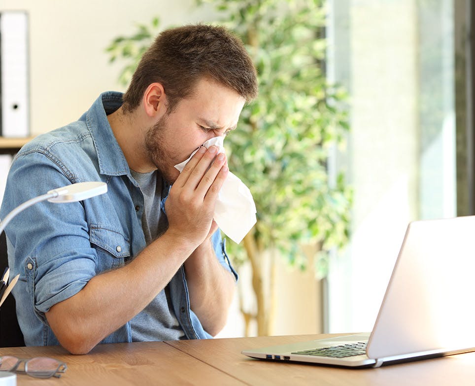 Hombre con congestión nasal limpiando su nariz. 