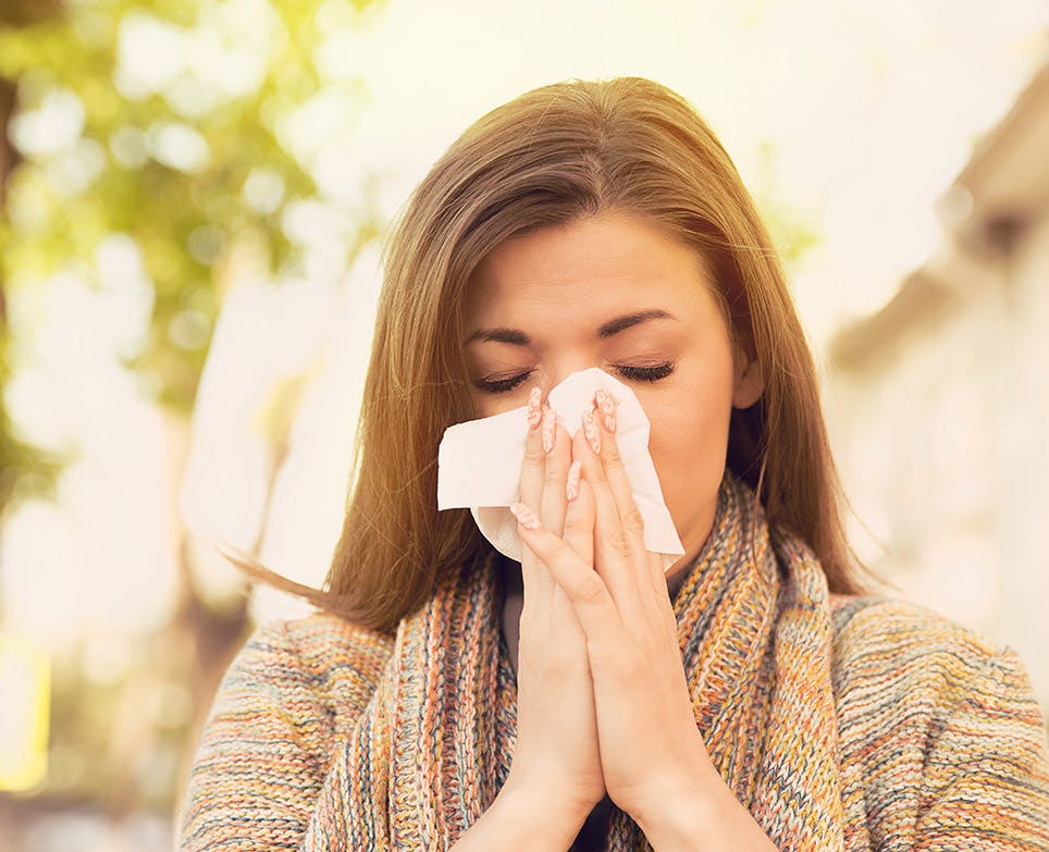 Mujer con síntomas gripales limpiando su nariz. 