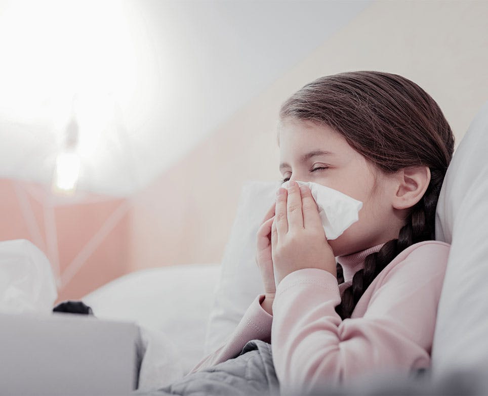 Niña con síntomas de congestión nasal limpiando su nariz.