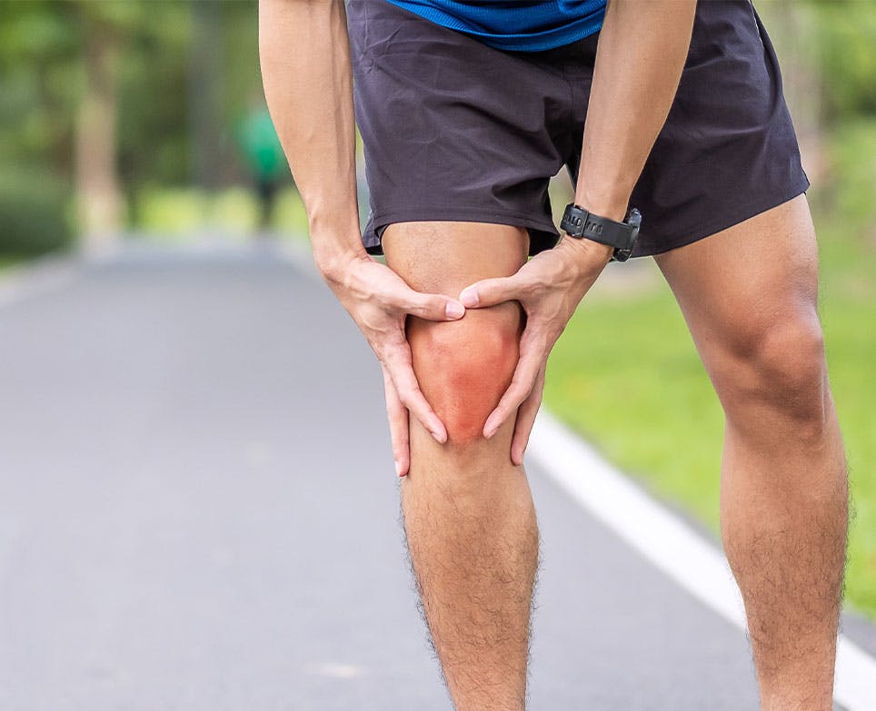 Hombre deportista agarrando su rodilla en señal de dolor.