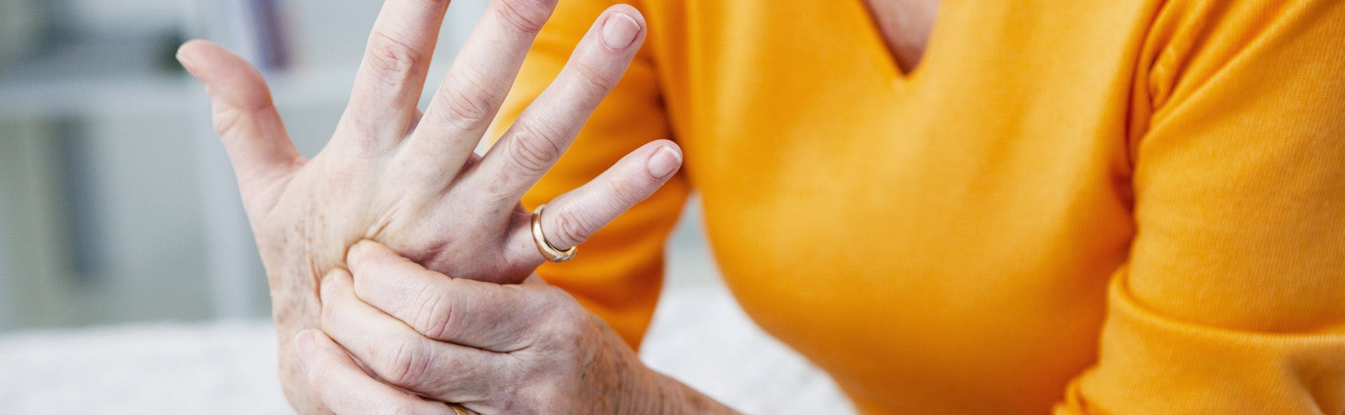 Mujer frotando su mano en señal de dolor.