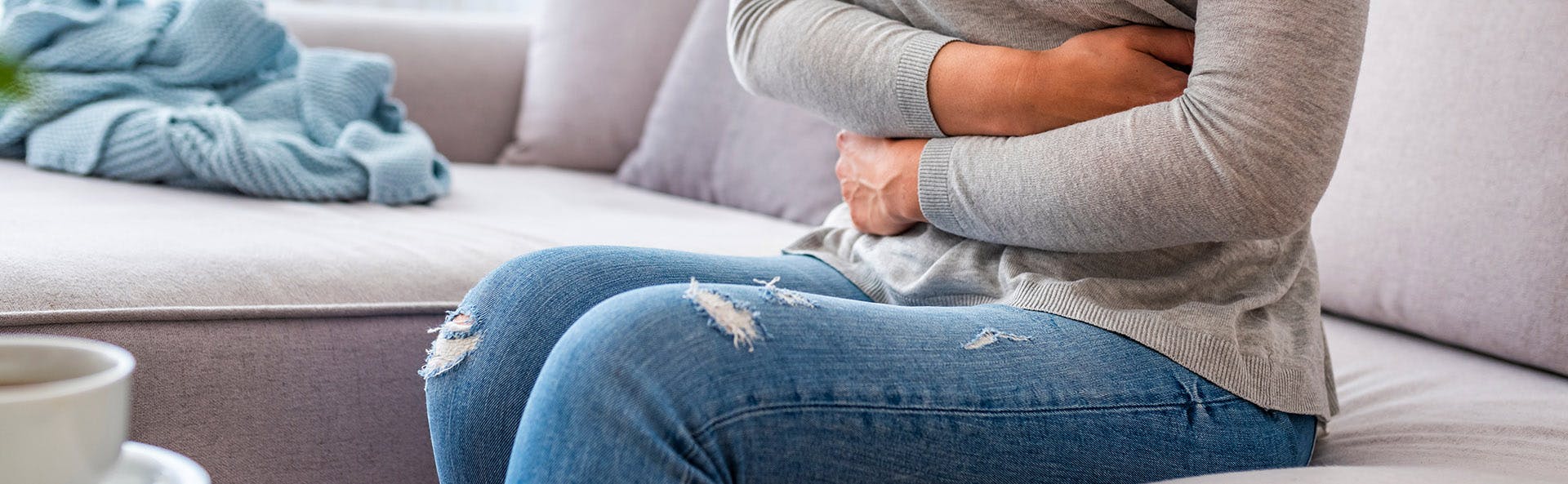 Mujer apretando su abdomen en señal de dolor.