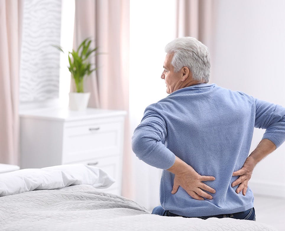 Hombre mayor con sus manos en la espalda baja, en señal de dolor. Hombre mayor con sus manos en la espalda baja, en señal de dolor.