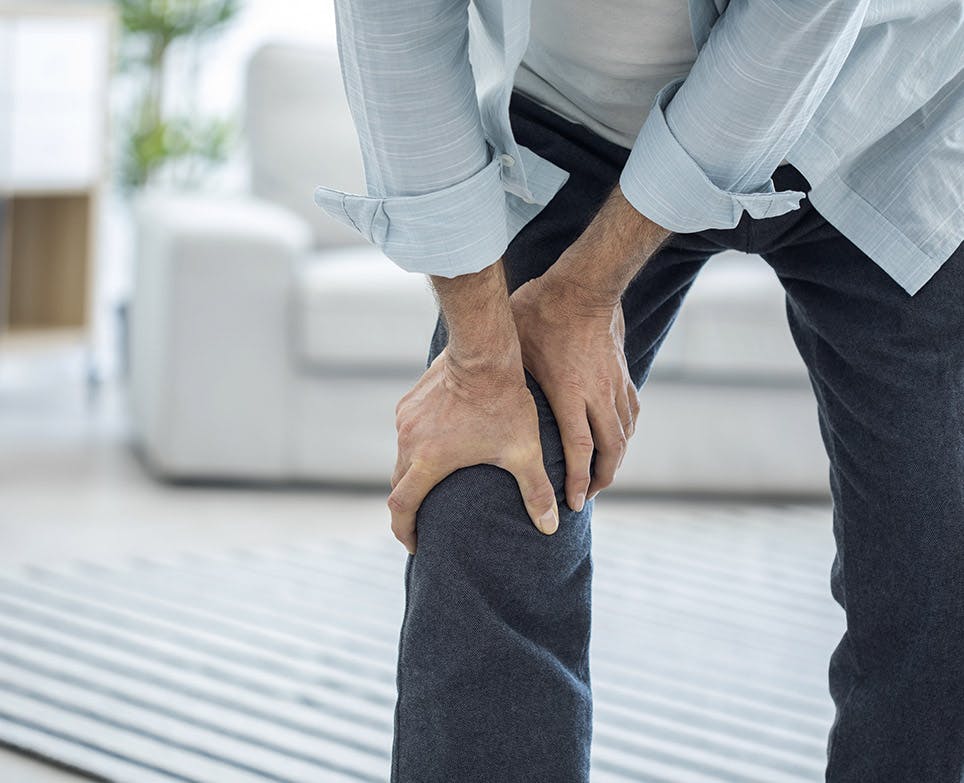 Hombre agarrando su rodilla en señal de dolor.