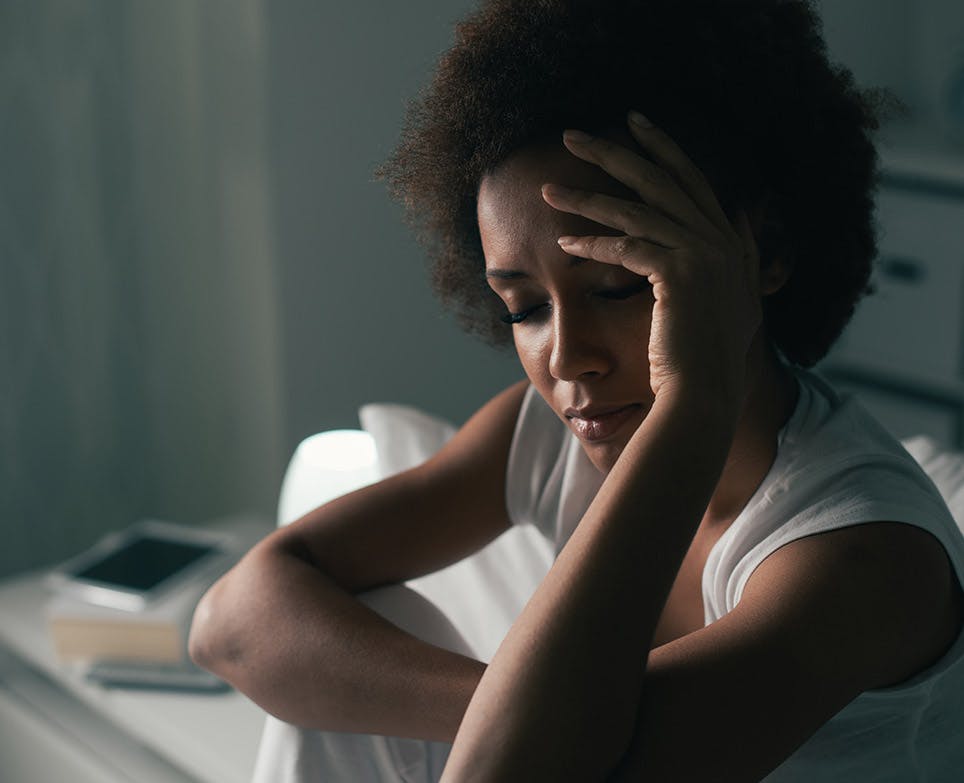 Mujer toca su cabeza en señal de dolor.