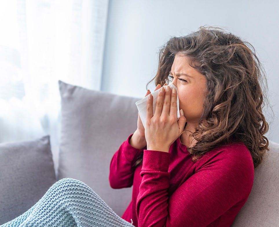 Mujer con síntomas de congestión nasal, limpiando su nariz.