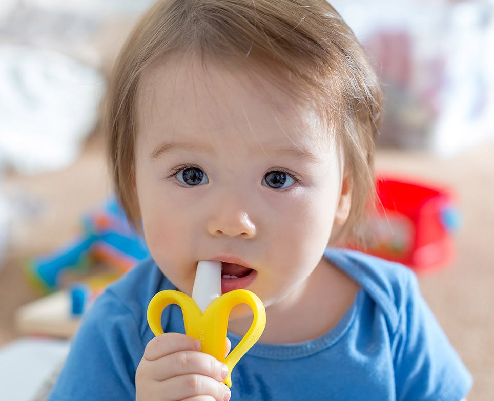 Una bebé mordiendo un juguete para dentición.