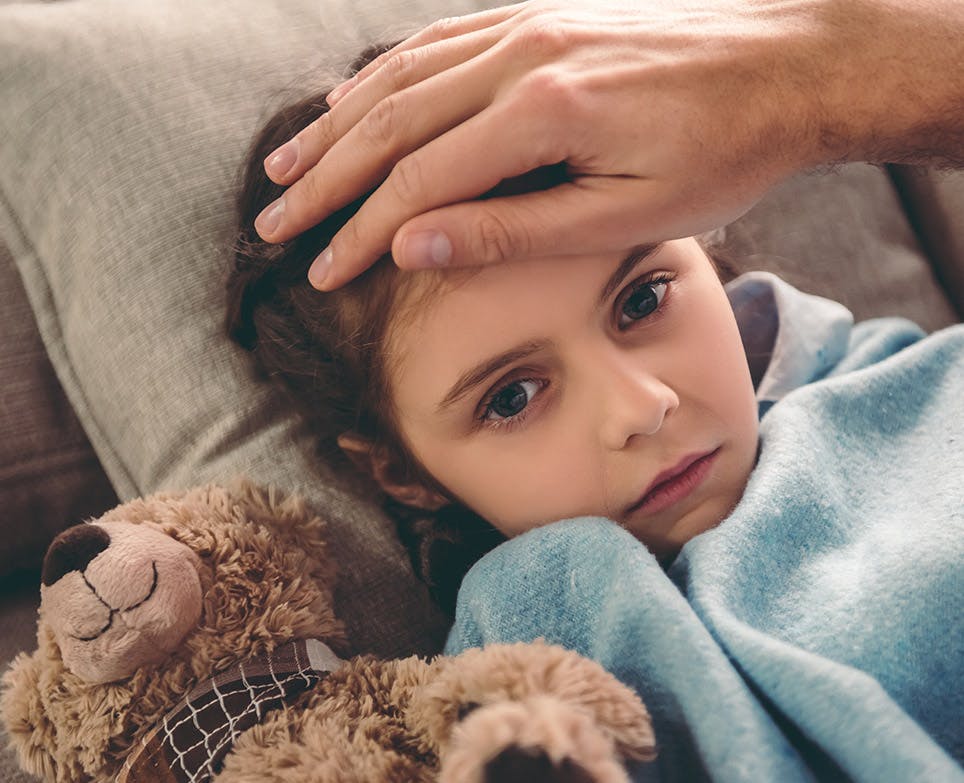 Mano de un hombre que toca la frente de su hija para verificar temperatura. Mano de un hombre que toca la frente de su hija para verificar temperatura.