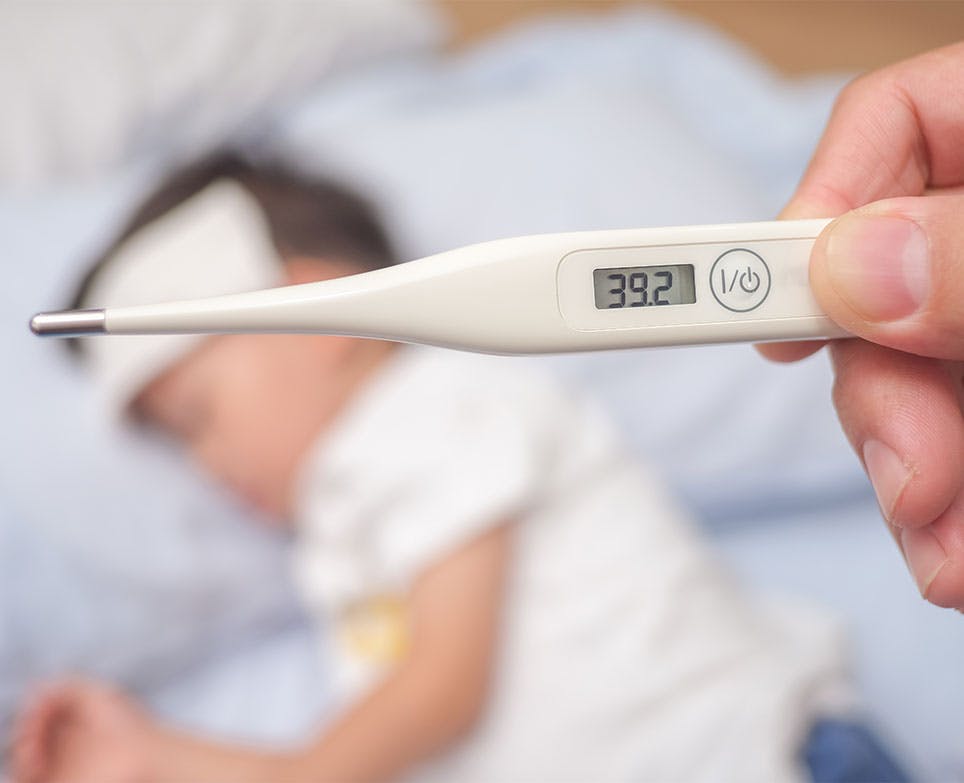 Toma de temperatura de un niño con termómetro digital. 