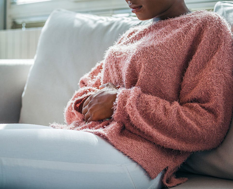 Mujer joven tocando su abdomen en señal de dolor menstrual. 