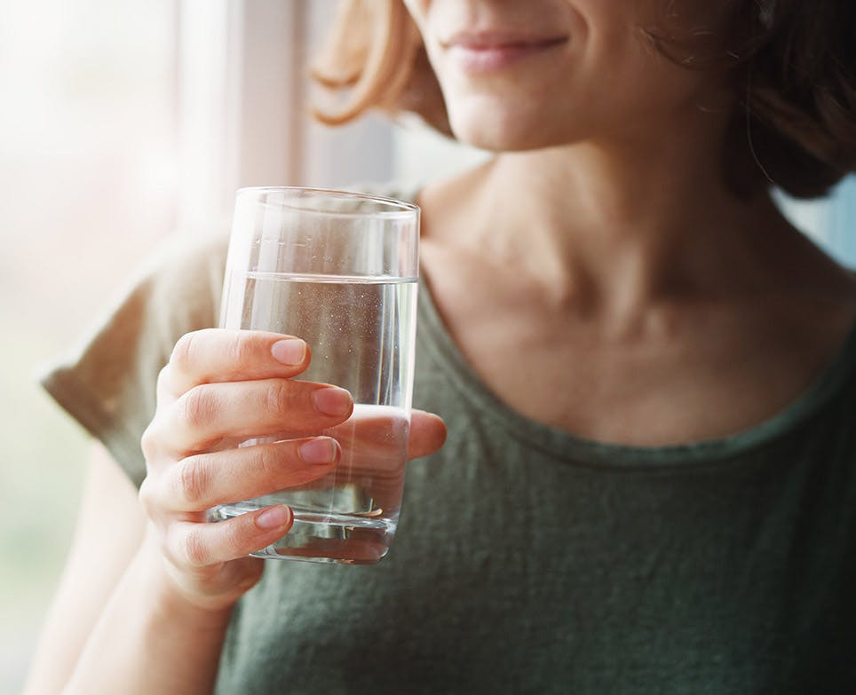 Mujer sosteniendo un vaso de agua. 