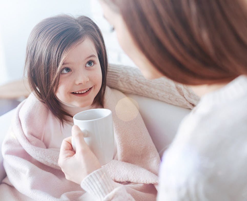 Madre abraza a su hija, al fondo se ve un doctor. 