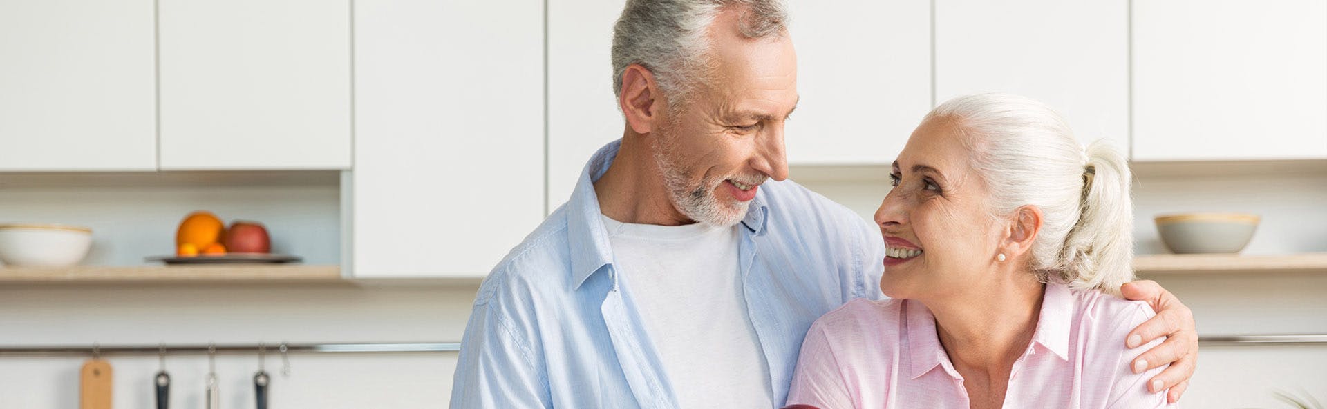 Zolben - Pareja de ancianos abrazándose y sonriendo en una cocina