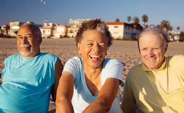 Tre ældre venner slapper af på stranden