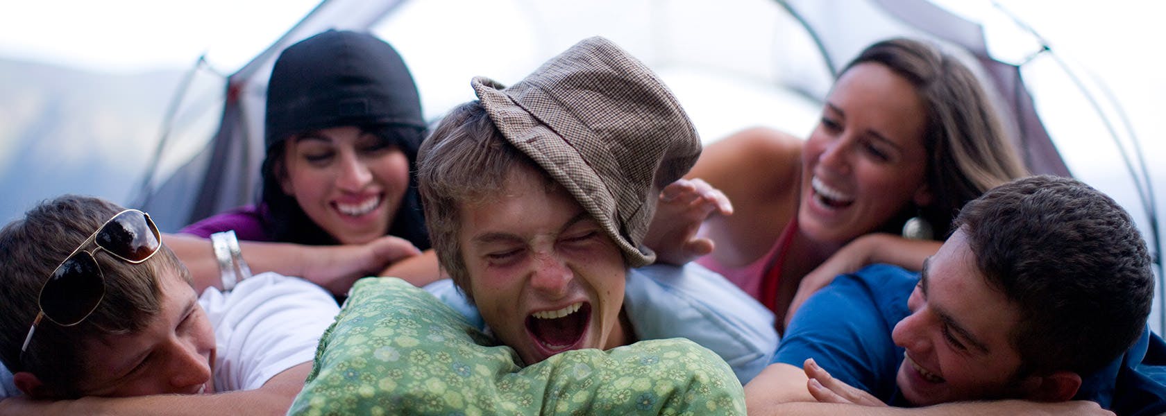 Stressfrie unge mennesker ligger sammen i telt og ler 