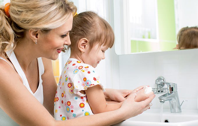 Et barn vasker hænder sammen med sin mor