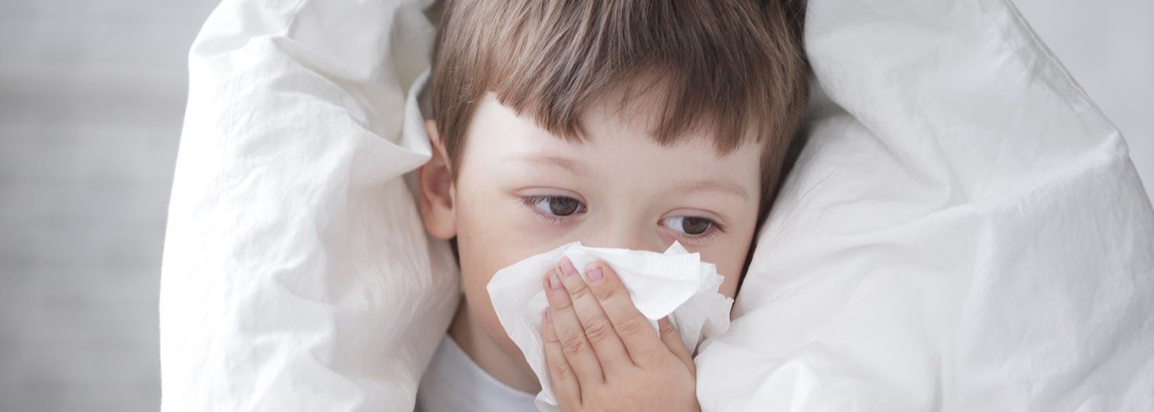 Child with flu blowing his nose