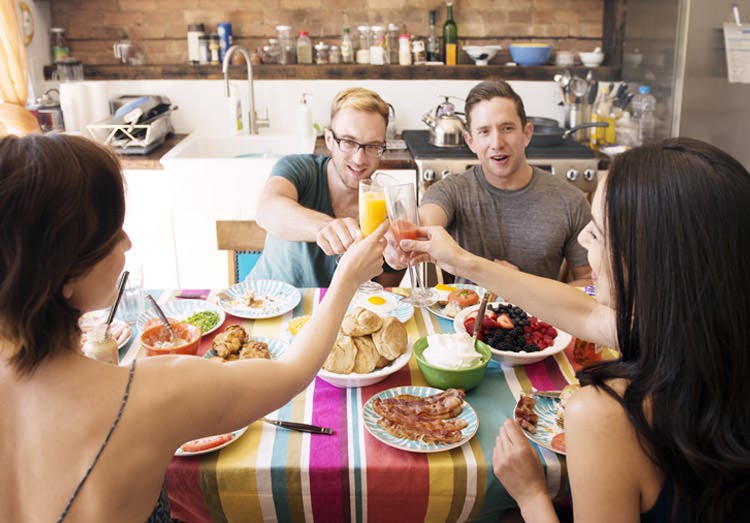 Friends Raise Their Glasses Together In A Toast At Breakfast Friends Raise Their Glasses Together In A Toast At Breakfast