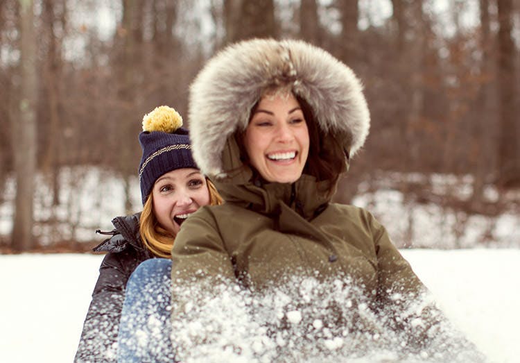Two Women Having Fun Sledding In Woods Two Women Having Fun Sledding In Woods