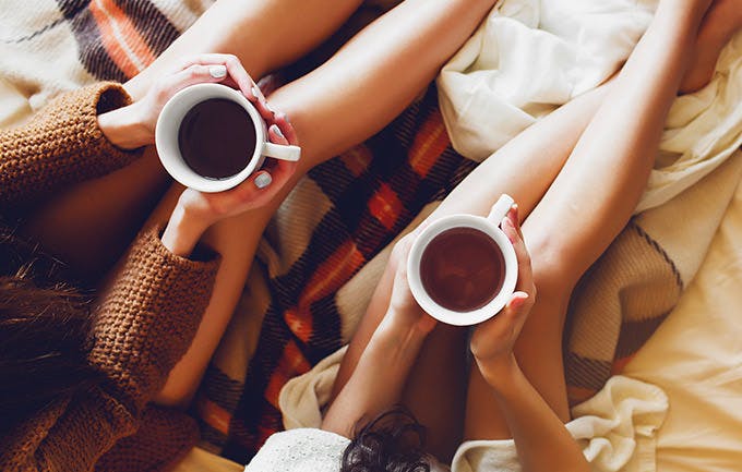 Two Sisters In Bedroom With Old Books And Cup Of Tea In Hands Wearing Cozy Sweater Two Sisters In Bedroom With Old Books And Cup Of Tea In Hands Wearing Cozy Sweater