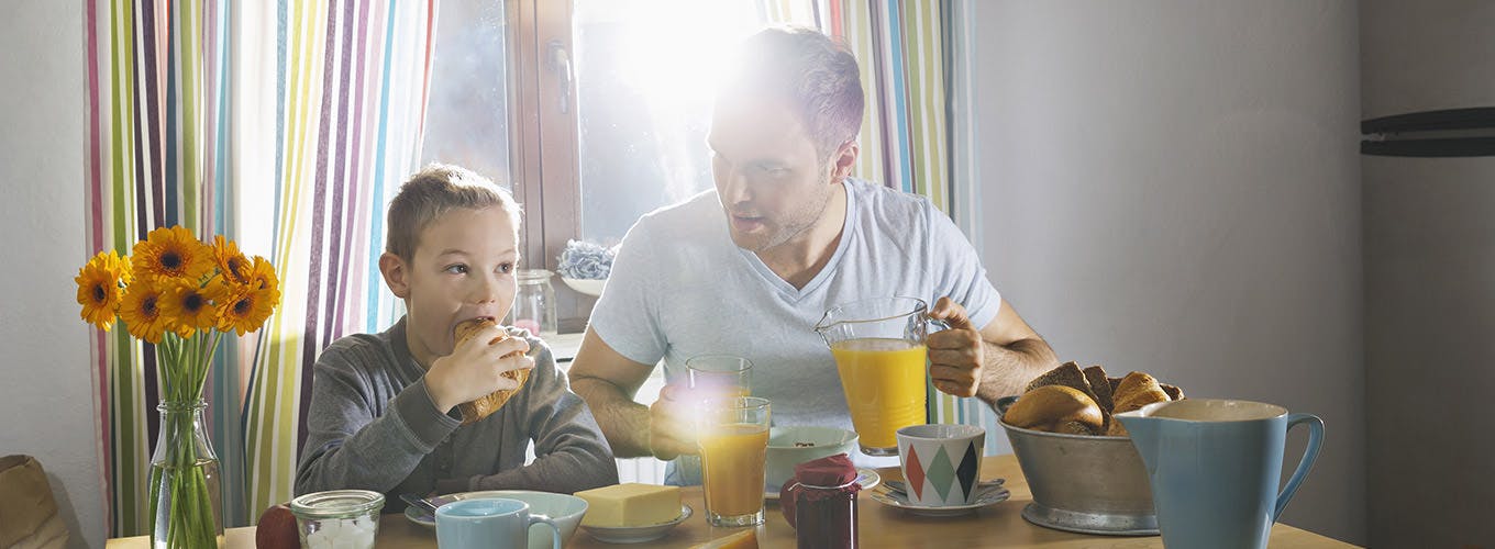 Father And Son Sitting At Breakfast Table
