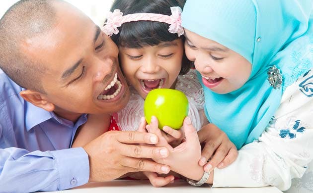 Father, mother and daughter getting ready to bite an apple
