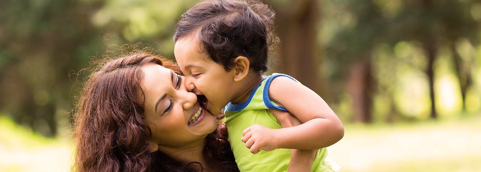 Happy Little Indian Boy Kissing Mother Outdoors
