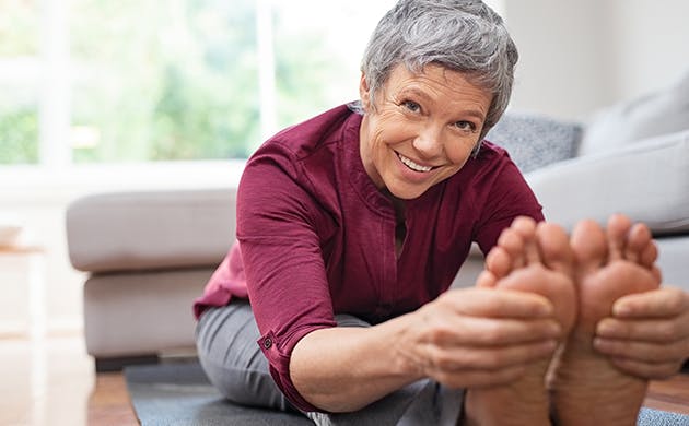 Mujer de la tercera edad estirando en casa - Dolex Colombia