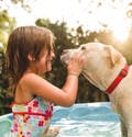 Una niña juega al aire libre con un perro.