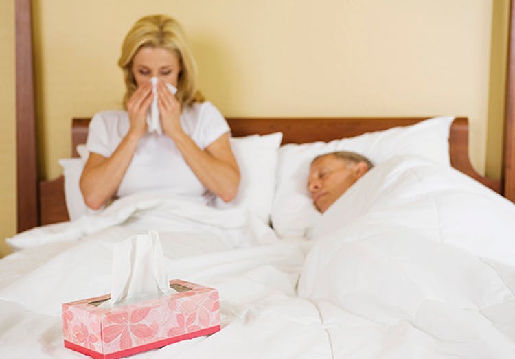 Pareja de adultos son sintomas gripales descansando en cama.