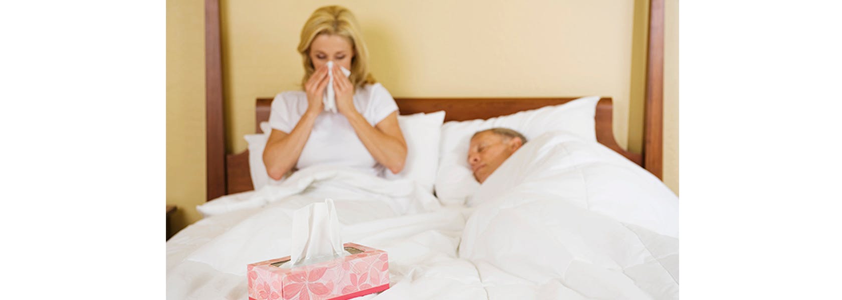Pareja de adultos son sintomas gripales descansando en cama.
