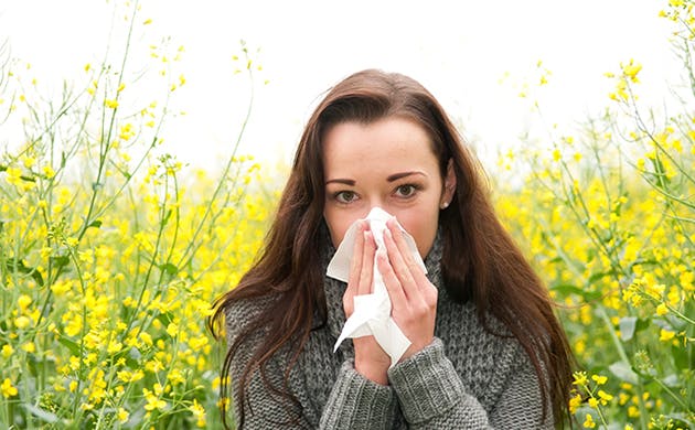 Mujer con síntomas gripales limpiando su nariz.