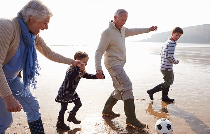 Abuelos jugando fútbol en la playa con sus nietos.