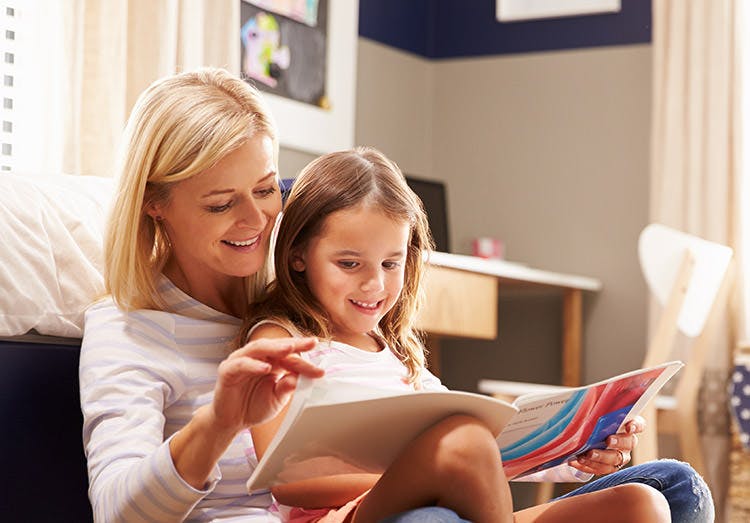 Madre e hija sonriendo y leyendo un libro