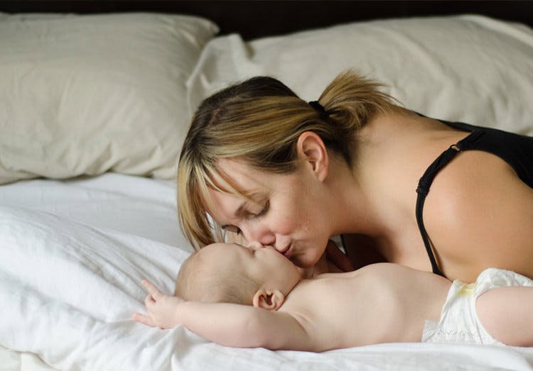 Ibu Mencium Bayinya di Atas Tempat Tidur