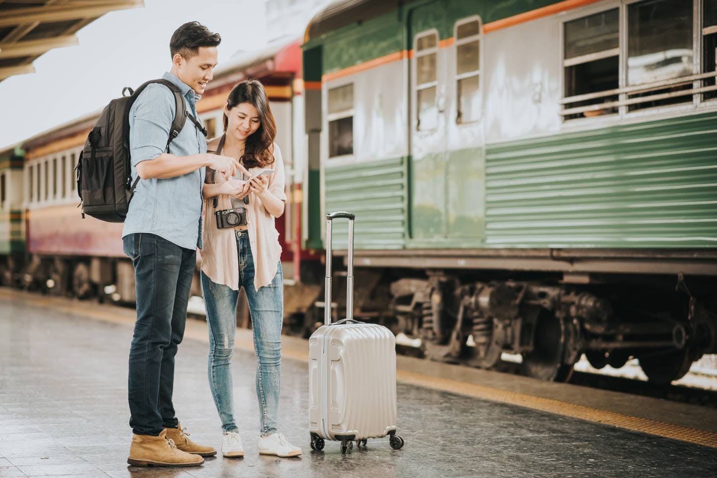 Couple checking travel schedule on a train platform