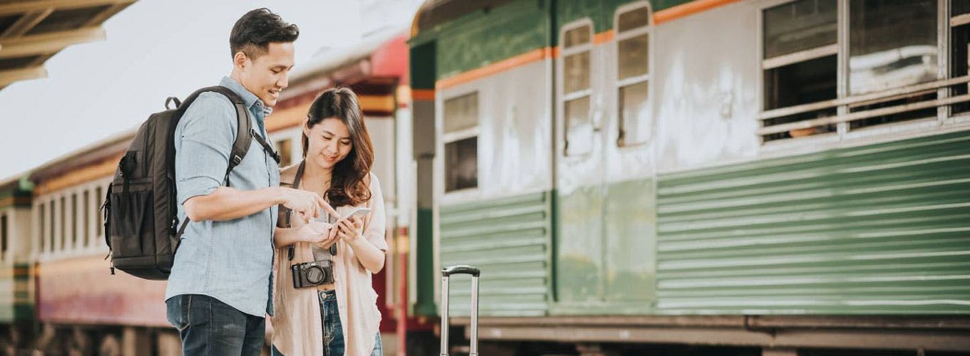 Couple checking travel schedule on a train platform