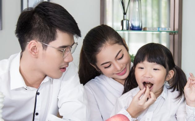 Father, mother and daughter getting ready to bite an apple