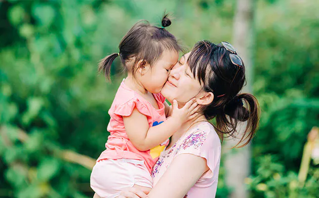 Mother carrying daughter in park