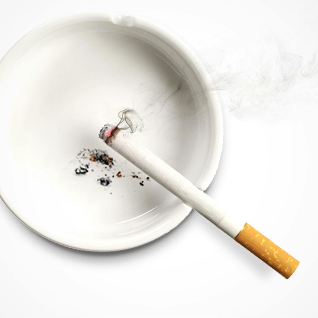 Zapálená cigareta opřená v popelníku