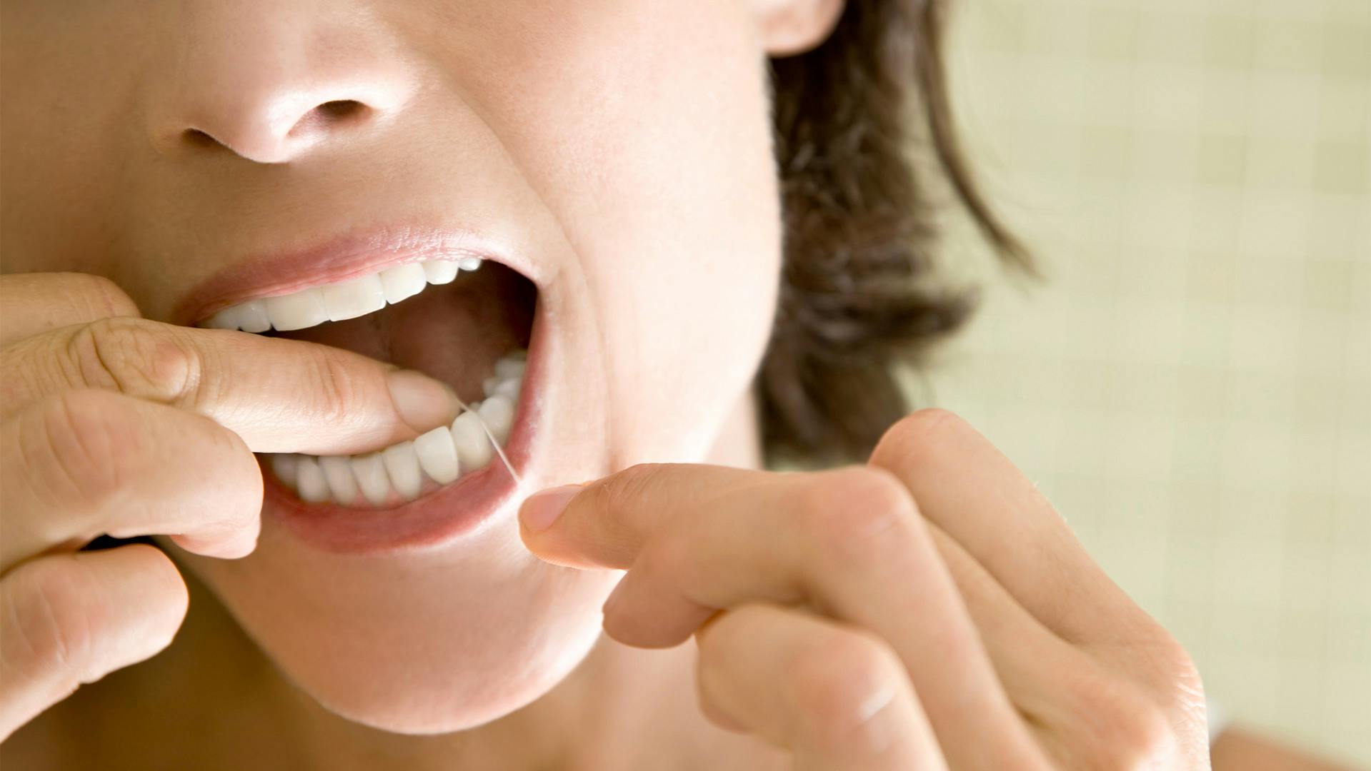 Žena, která si čistí mezizubní prostory zubní nití
