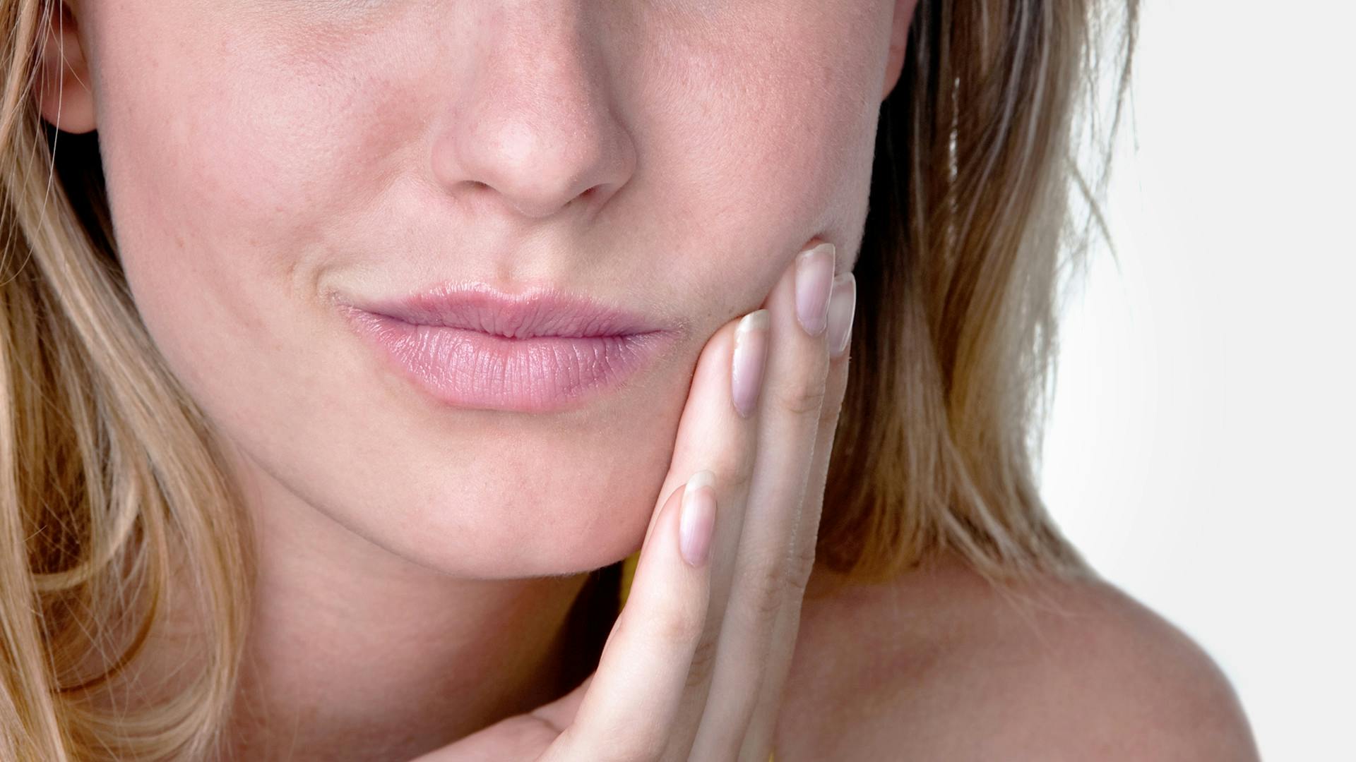 woman with mouth ulcer touching painful mouth and cheek