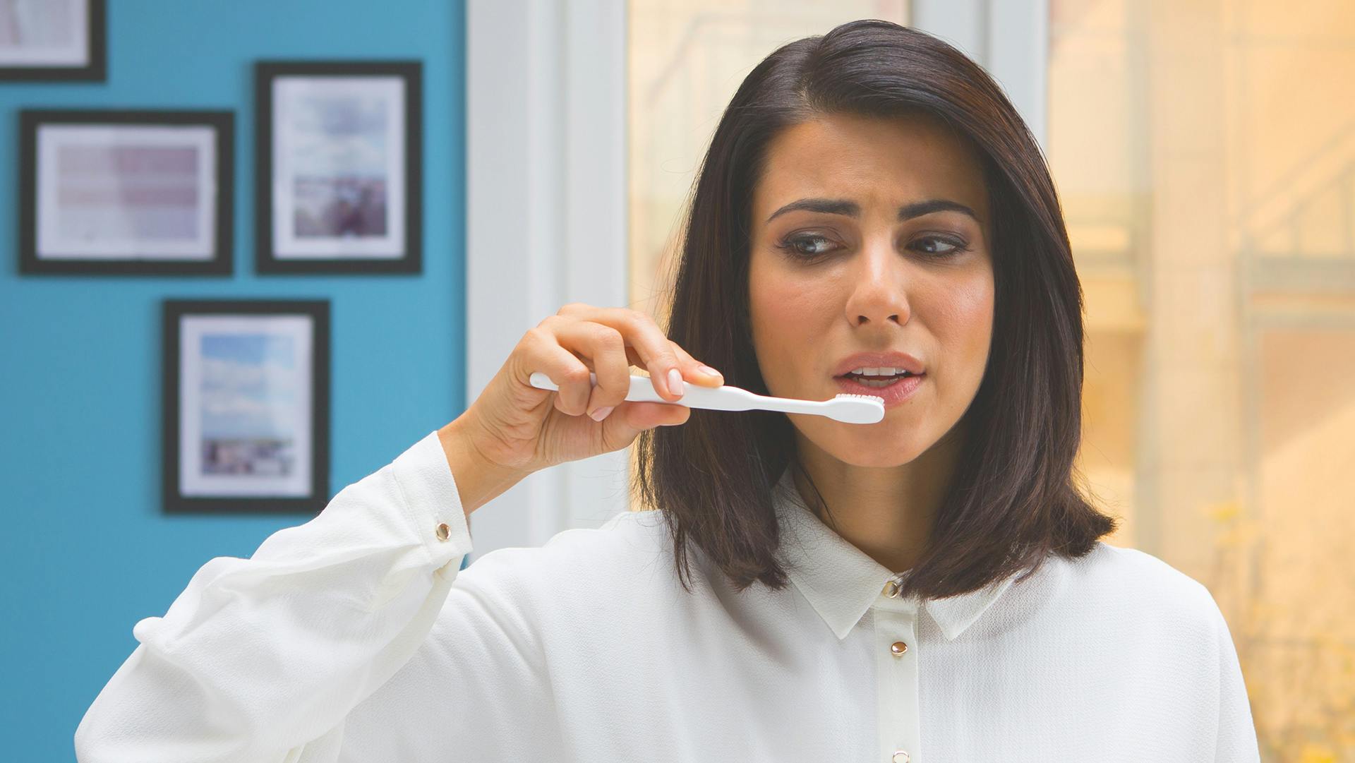 Γυναίκα κοιτάζει τον νιπτήρα κρατώντας την οδοντόβουρτσα της